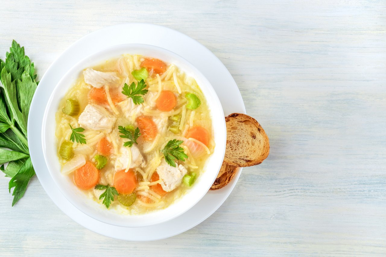 Chicken noodle soup shot from above with toasted bread and a place for text