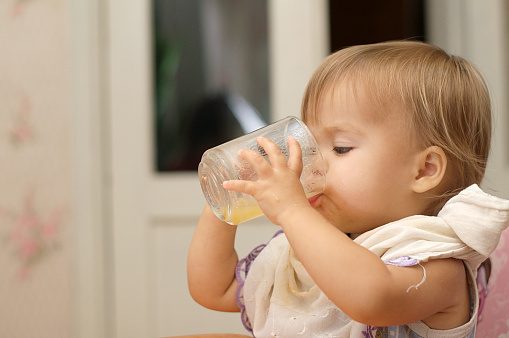 Caucasian blonde little girl drinking natural juice