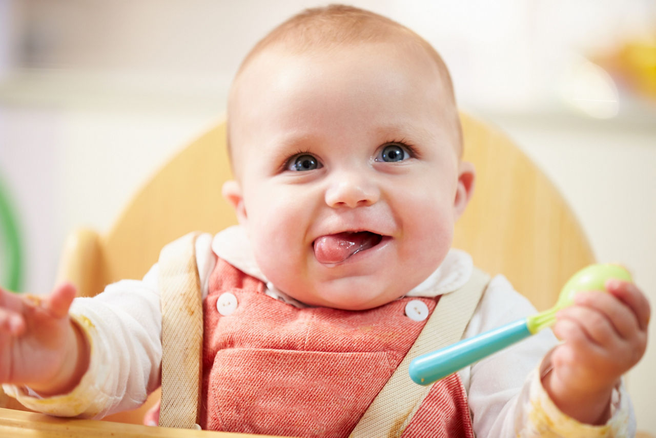 Portrait Of Happy Young Baby Boy In High Chair Waiting For Food