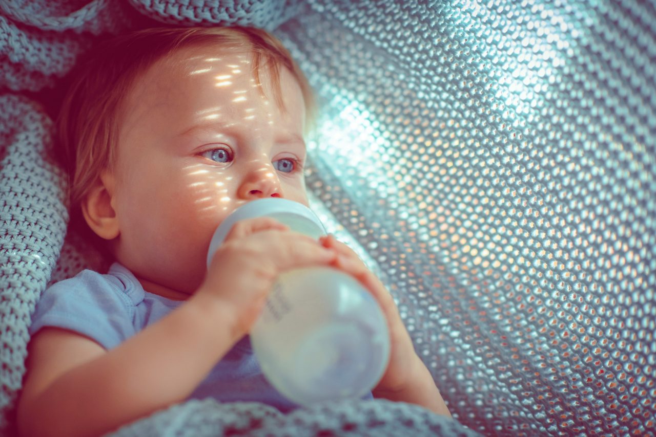 Cute baby boy drinking milk in the morning