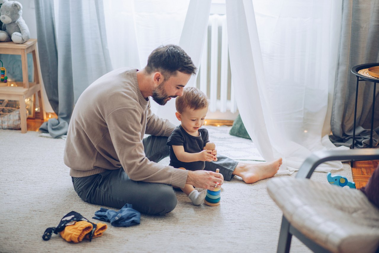 father playing with toddler and toys