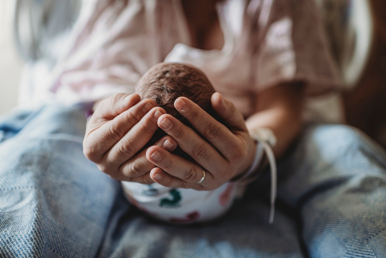Mama mit Geburtsverletzungen hält Baby in Händen