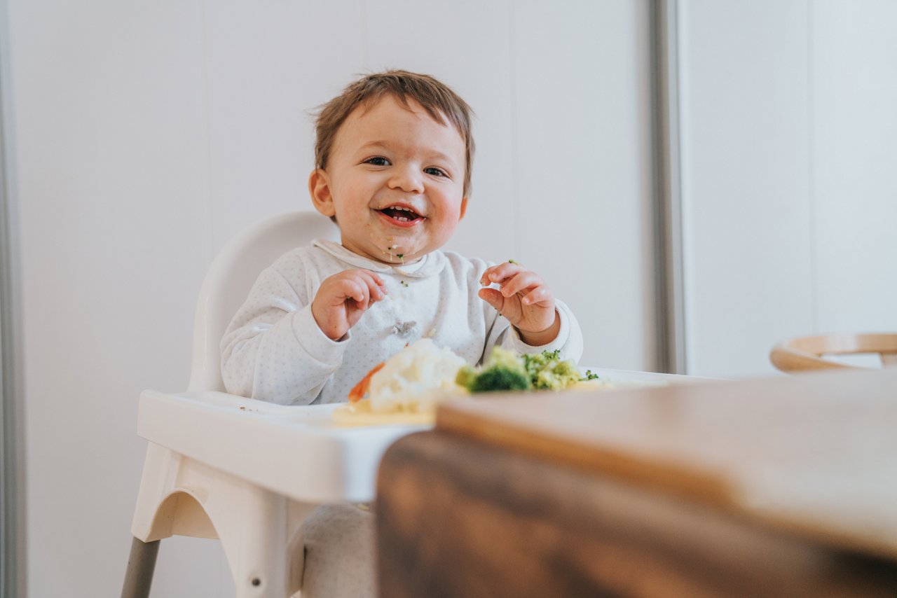 Baby im Kinderstuhl am Essen