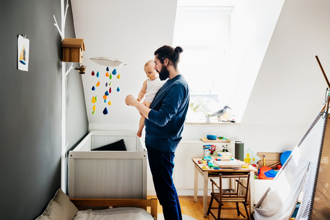 A single dad playing with his baby in the nursery at home.