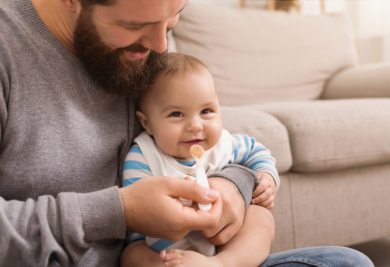 Father feeding a spoon of food to his baby