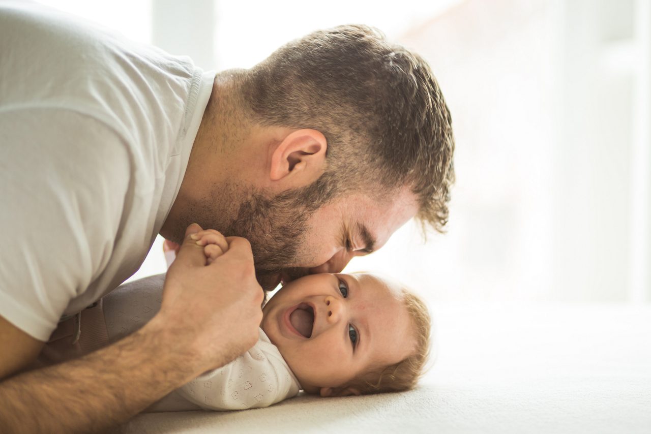 Happy mature father playing with his baby daughter (3 months old).