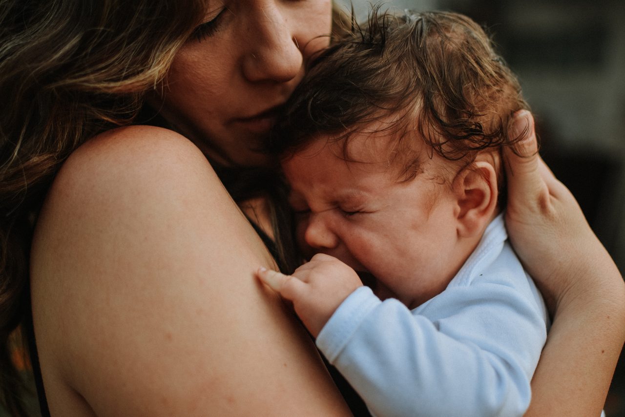 Ouder die een pasgeboren baby liefdevol vasthoudt tijdens een intiem moment van verbondenheid.