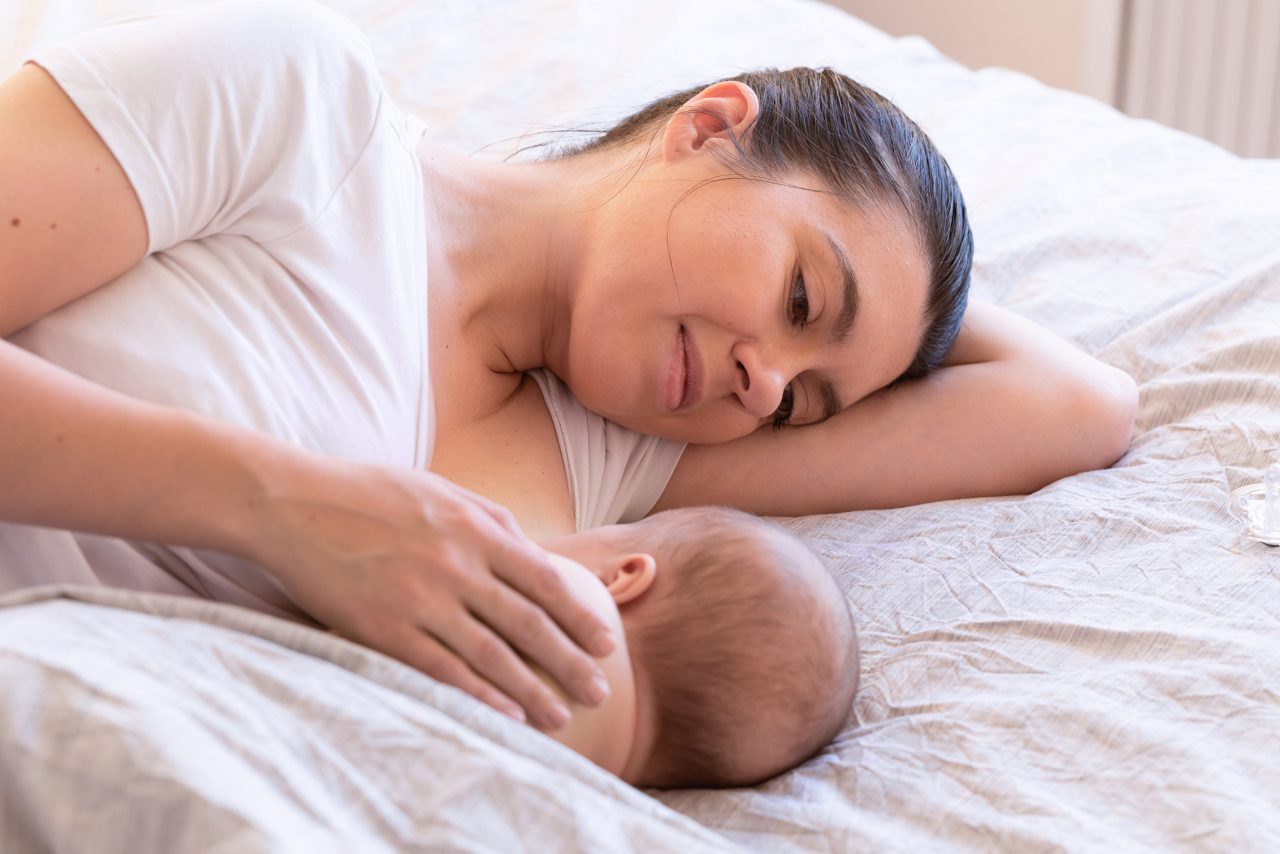 Close-up of mother breastfeeding and hugging newborn baby. Mom breast feeding her infant baby. Lactation newborn concept. Baby eating milk before sleeping. Mother feed her month son with breast milk