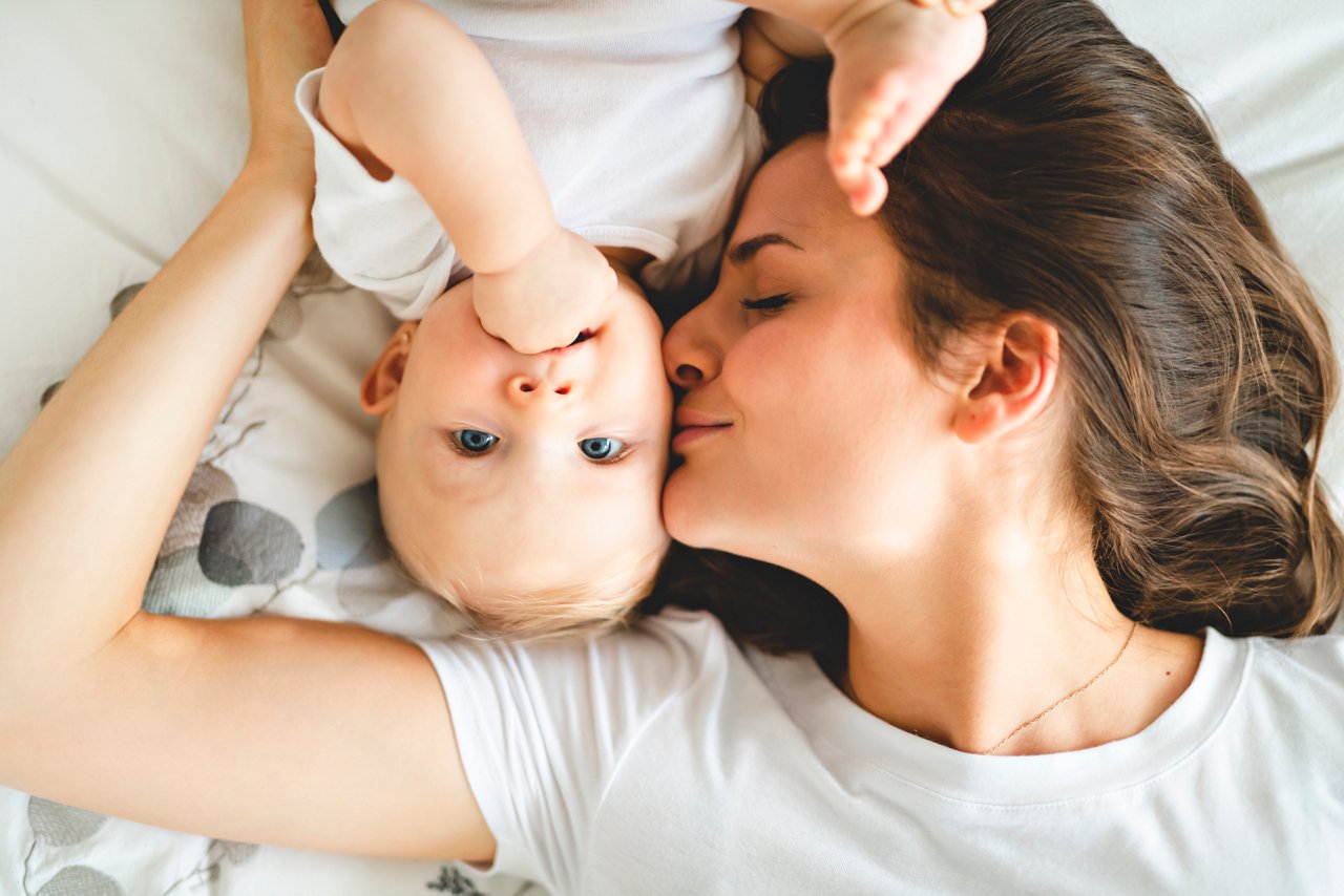 Mother kissing baby in bed