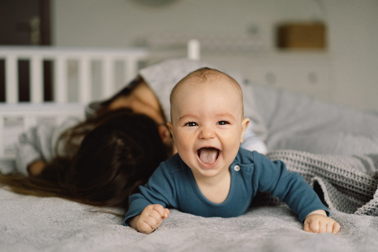 Baby liegt auf dem Bauch und lacht