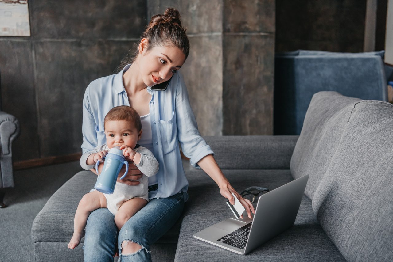 Mother on laptop while holding baby
