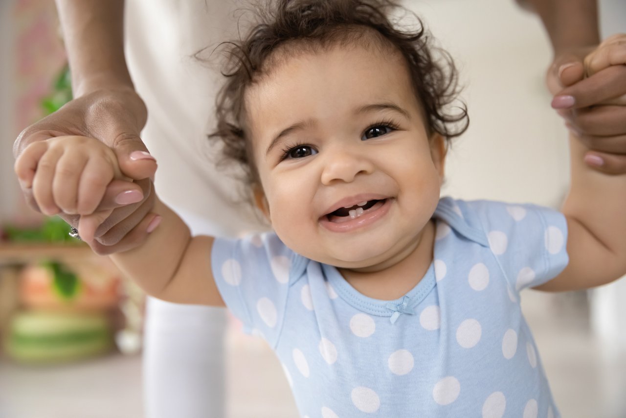 Baby steht und hält sich bei Mutter fest