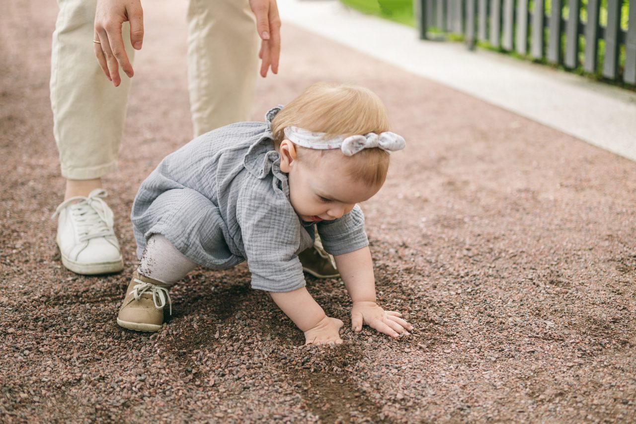 A one-year-old girl got dirty in the ground while walking. Walking with your child, letting touch the dirt, explore the world around you