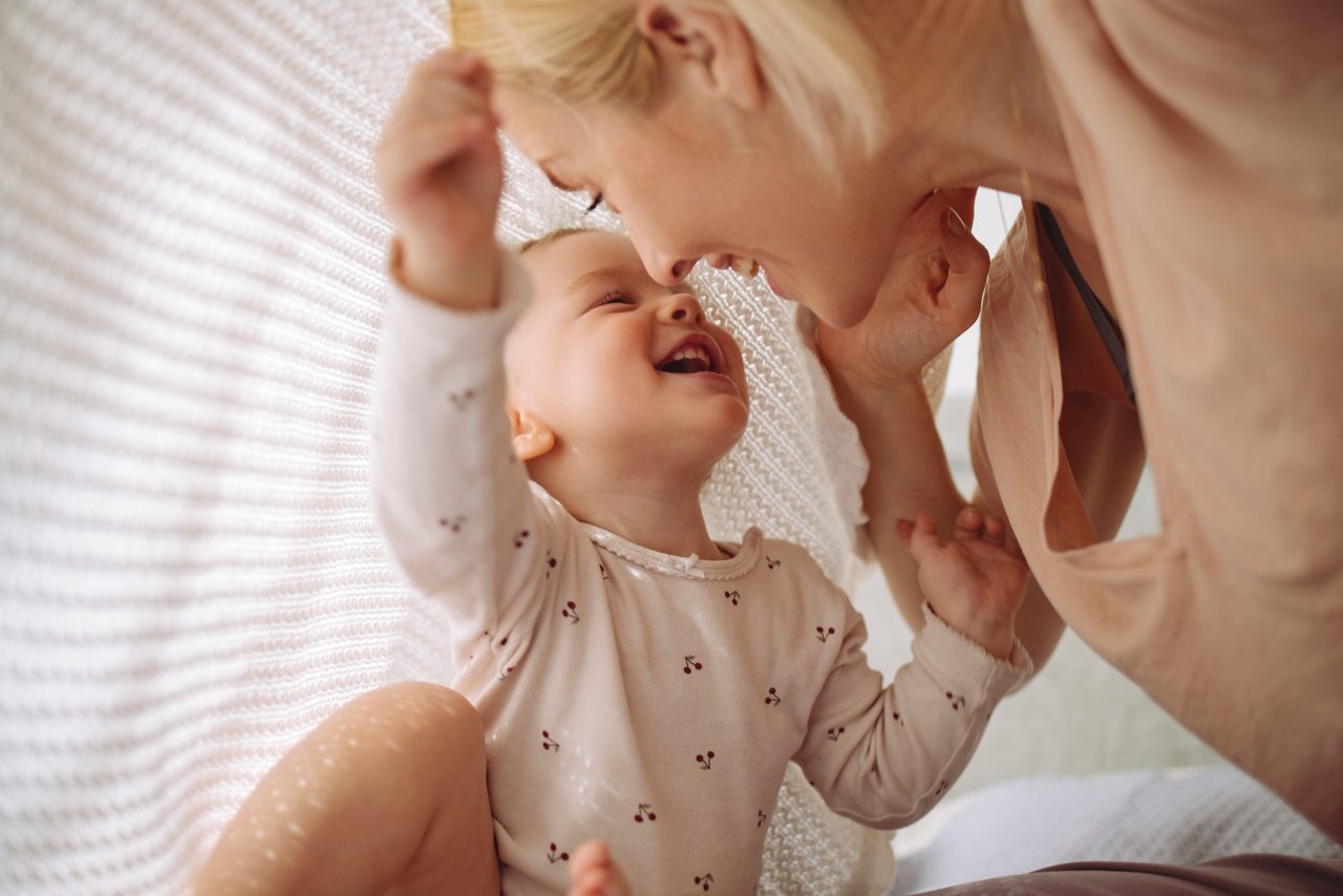 Kleindkind auf dem Schoß der Mama. Beide lachen zusammen.