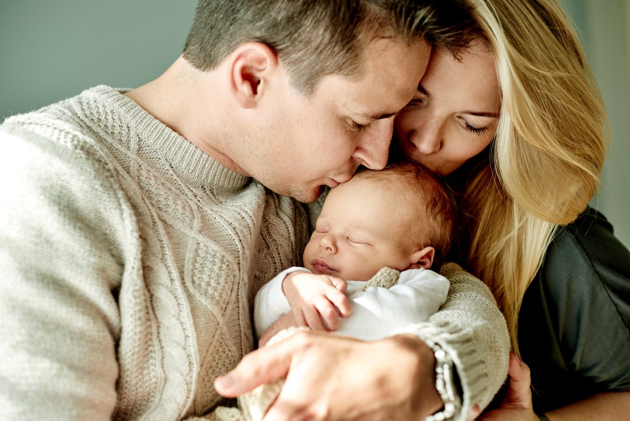 Parents kissing their newborn baby