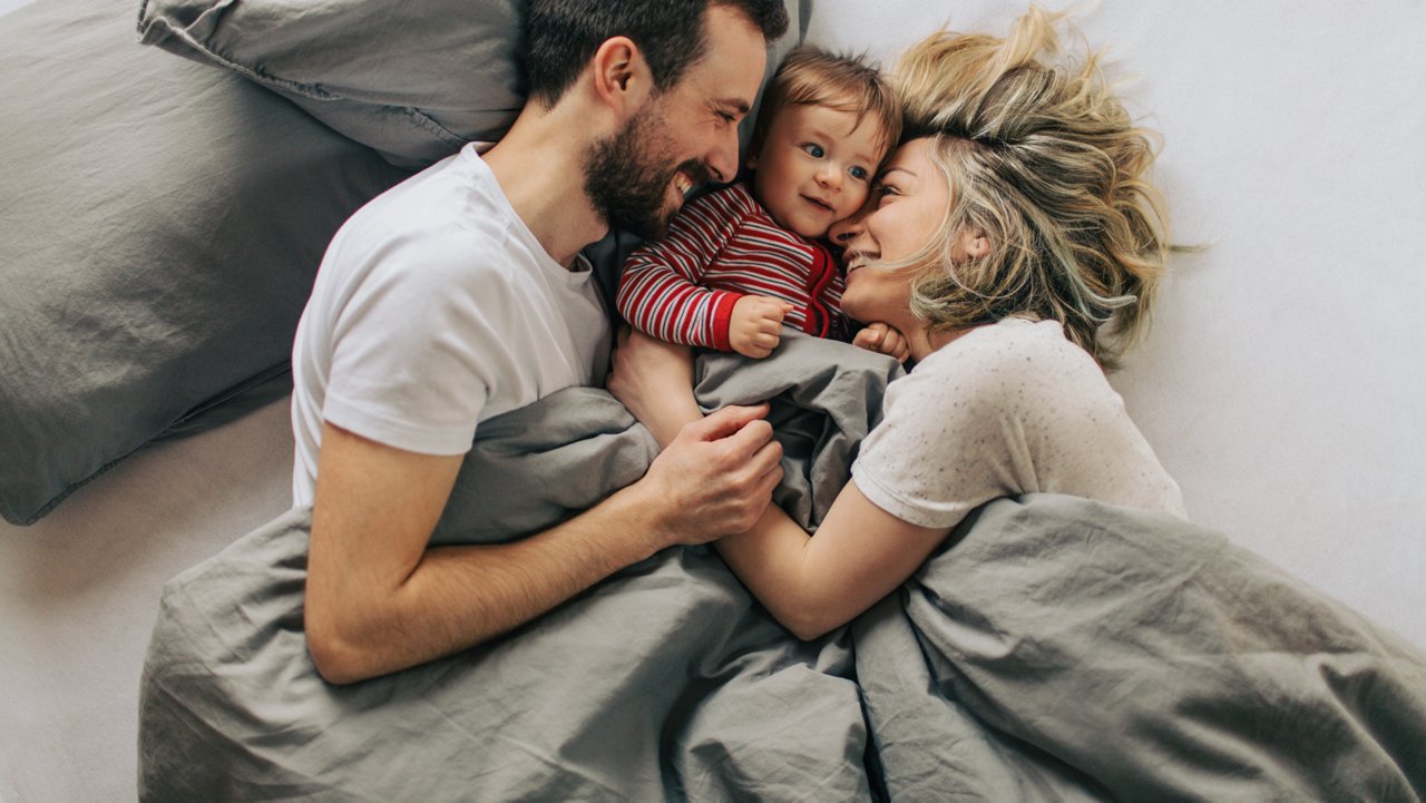 Kleinkind kuschelt mit Eltern im Bett