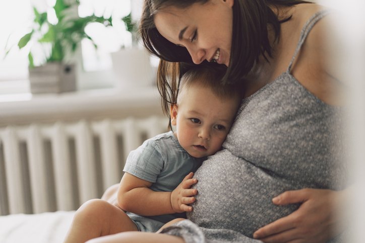 Mutter liegt mit zwei Kindern im Bett.