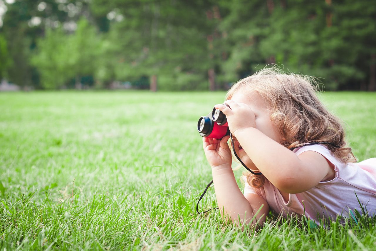 Toddler lookung through a binocular