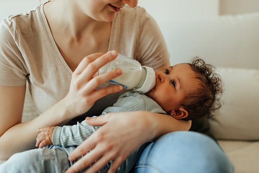 Mother sitting on couch breastfeeding her baby