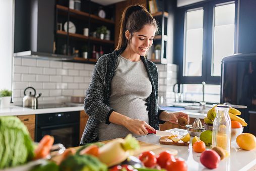 Pregnant woman cooking healthy meal in kitchen