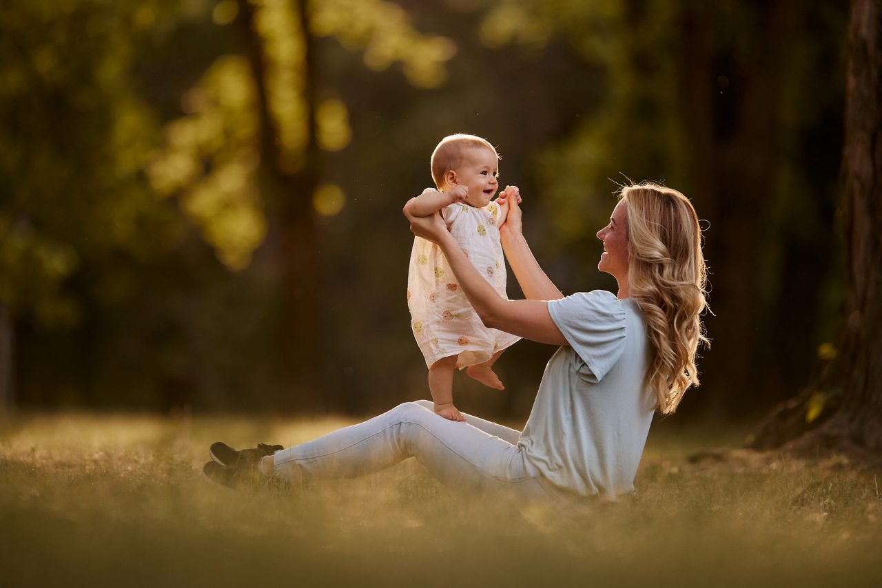 Happy mother is playing with her baby girl in the public park