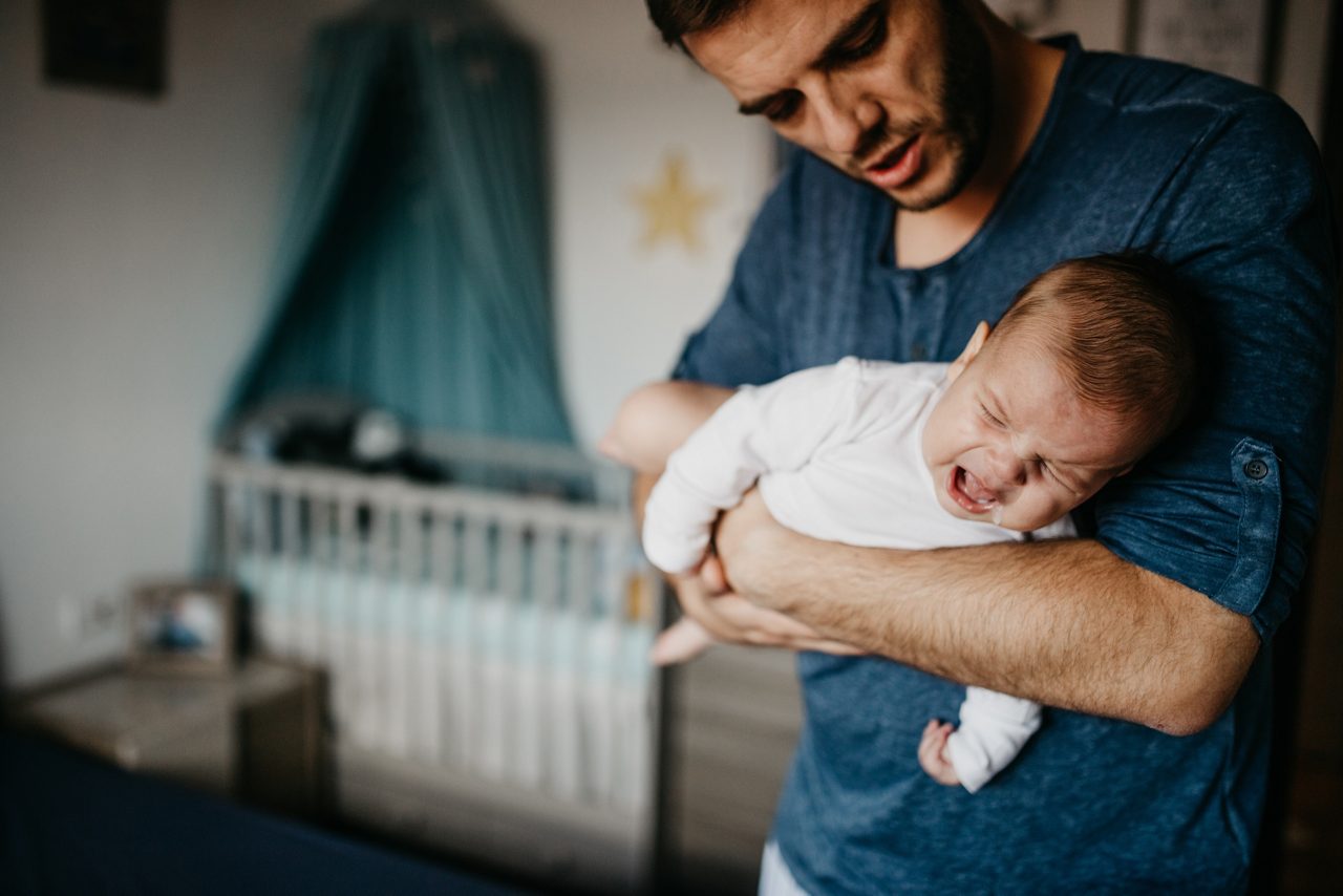 Dad Holding crying baby in the colic carry