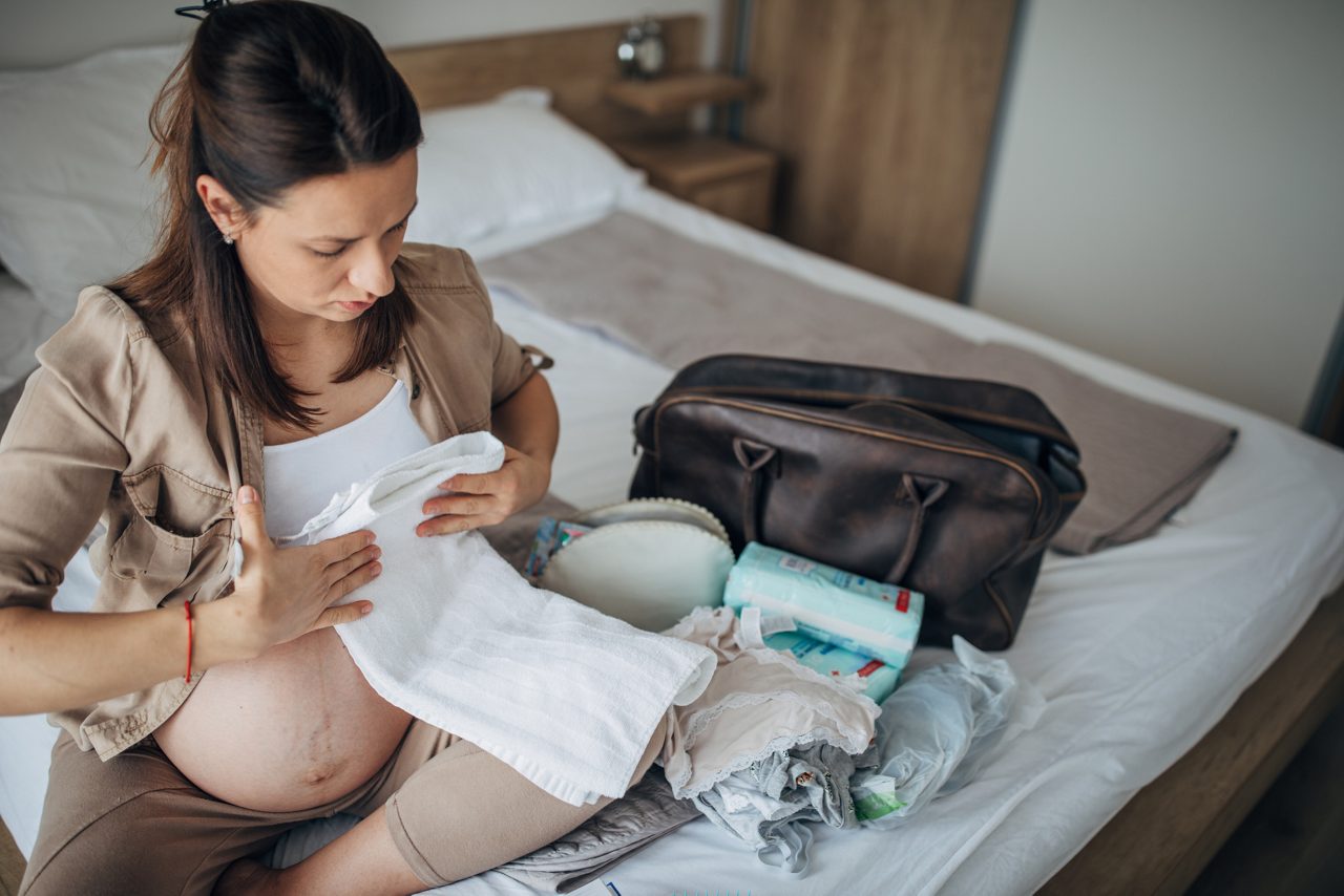 Schwangere Frau packt Kliniktasche