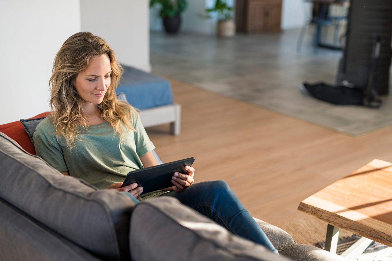 Woman realxing on couch at home using tablet