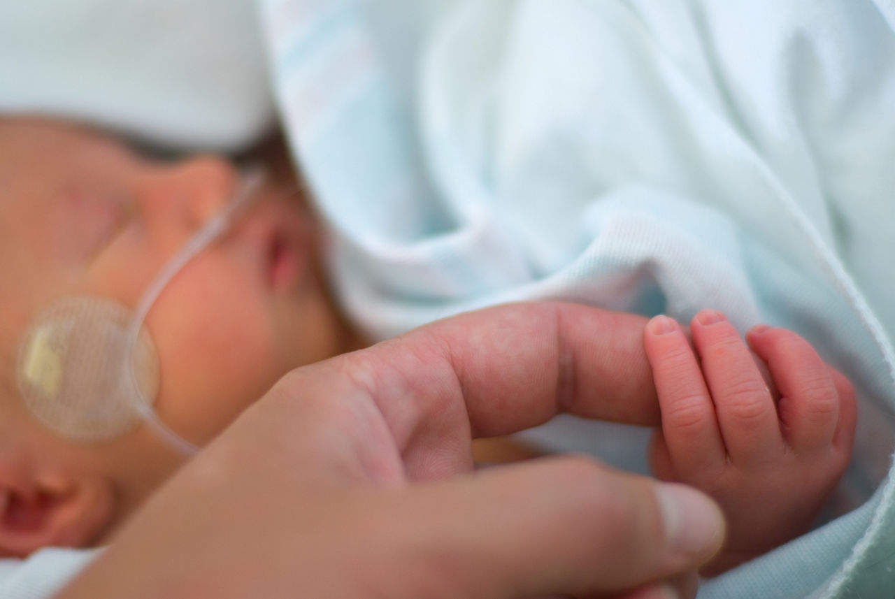 Mother holding baby's finger while is a hospital