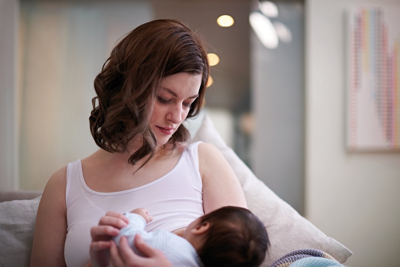 Mutter stillt ihr Baby auf Sofa