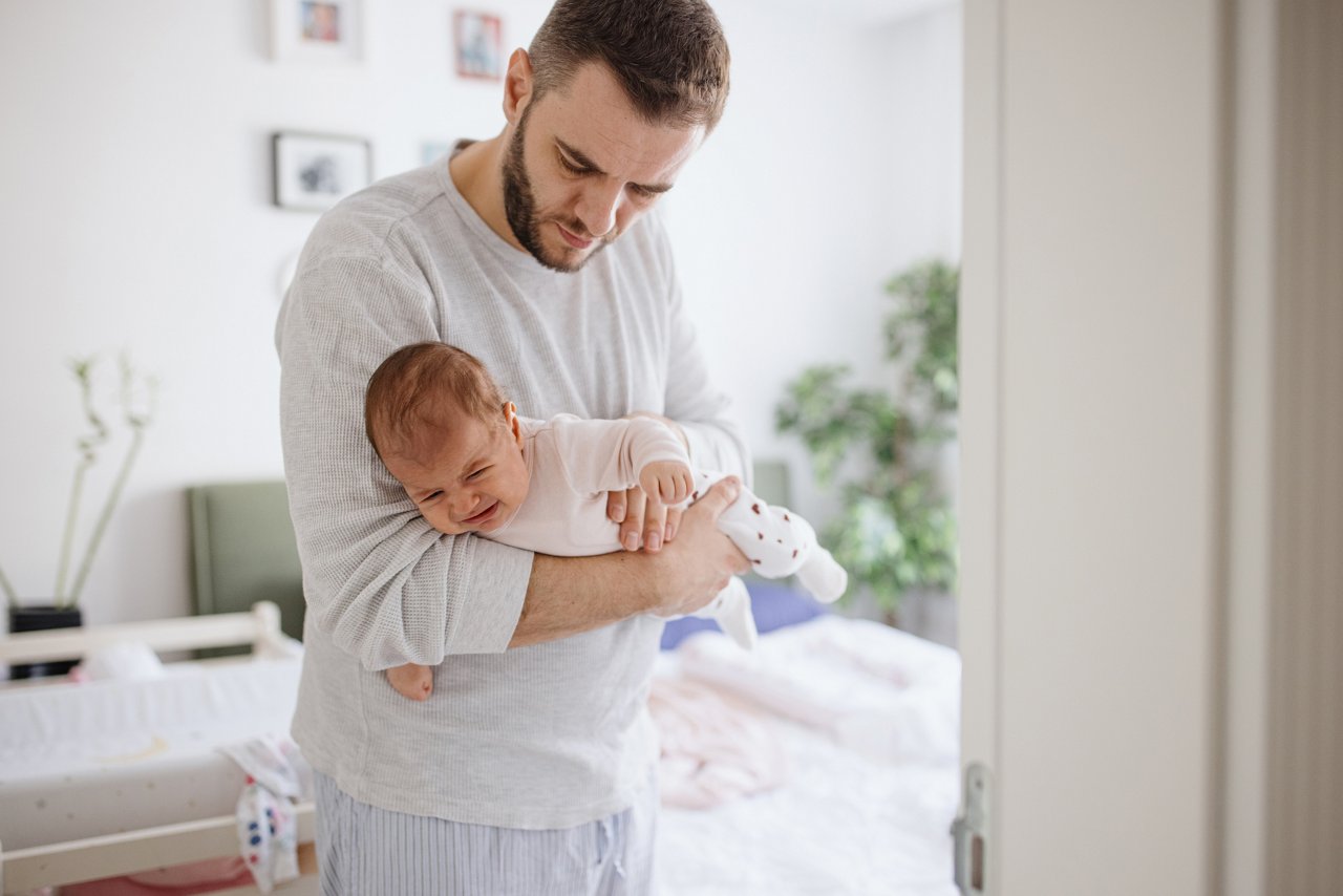 Baby auf dem Schoss der Mama, die es im Fliegergriff hält.