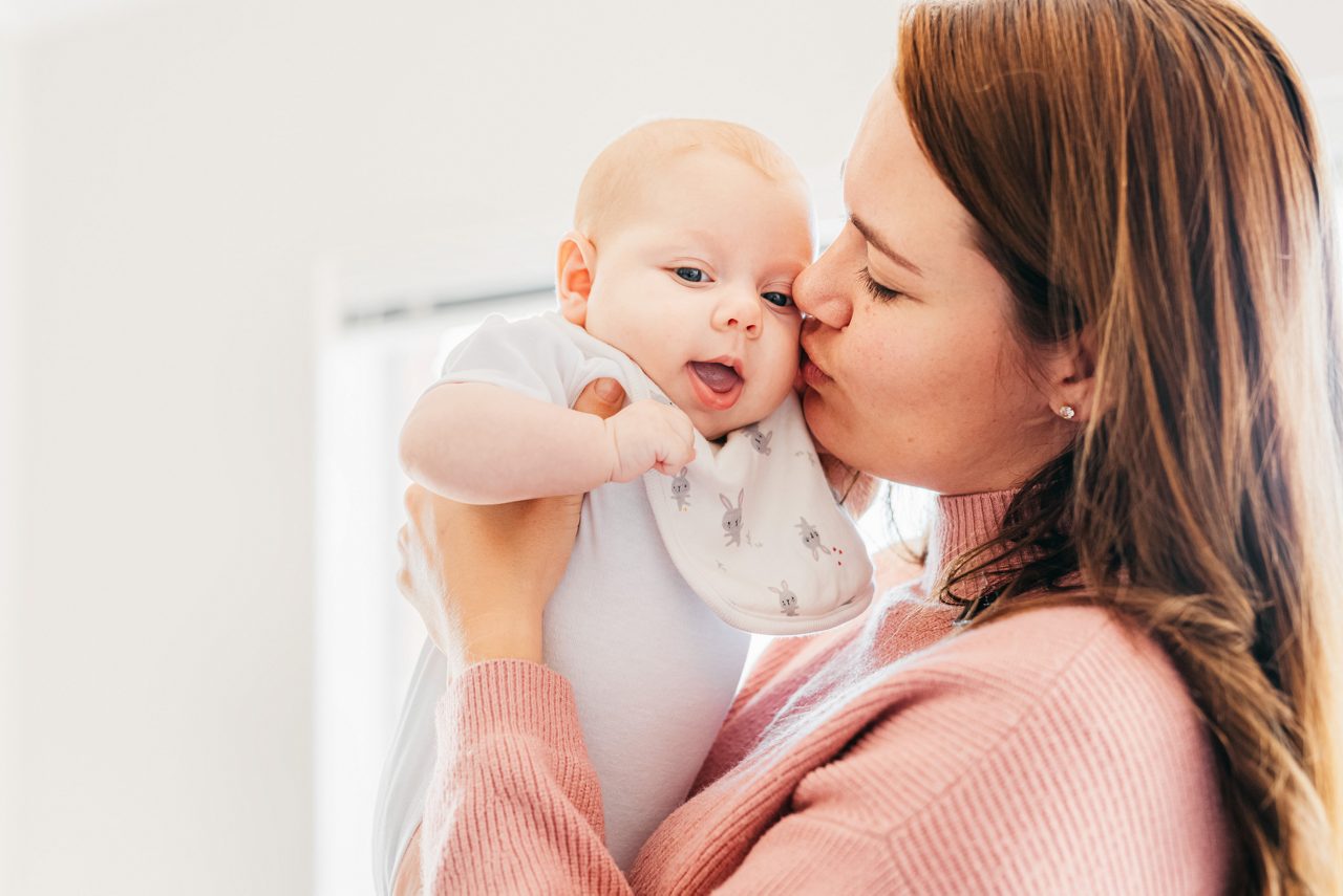 Mutter küsst Baby auf die Wange
