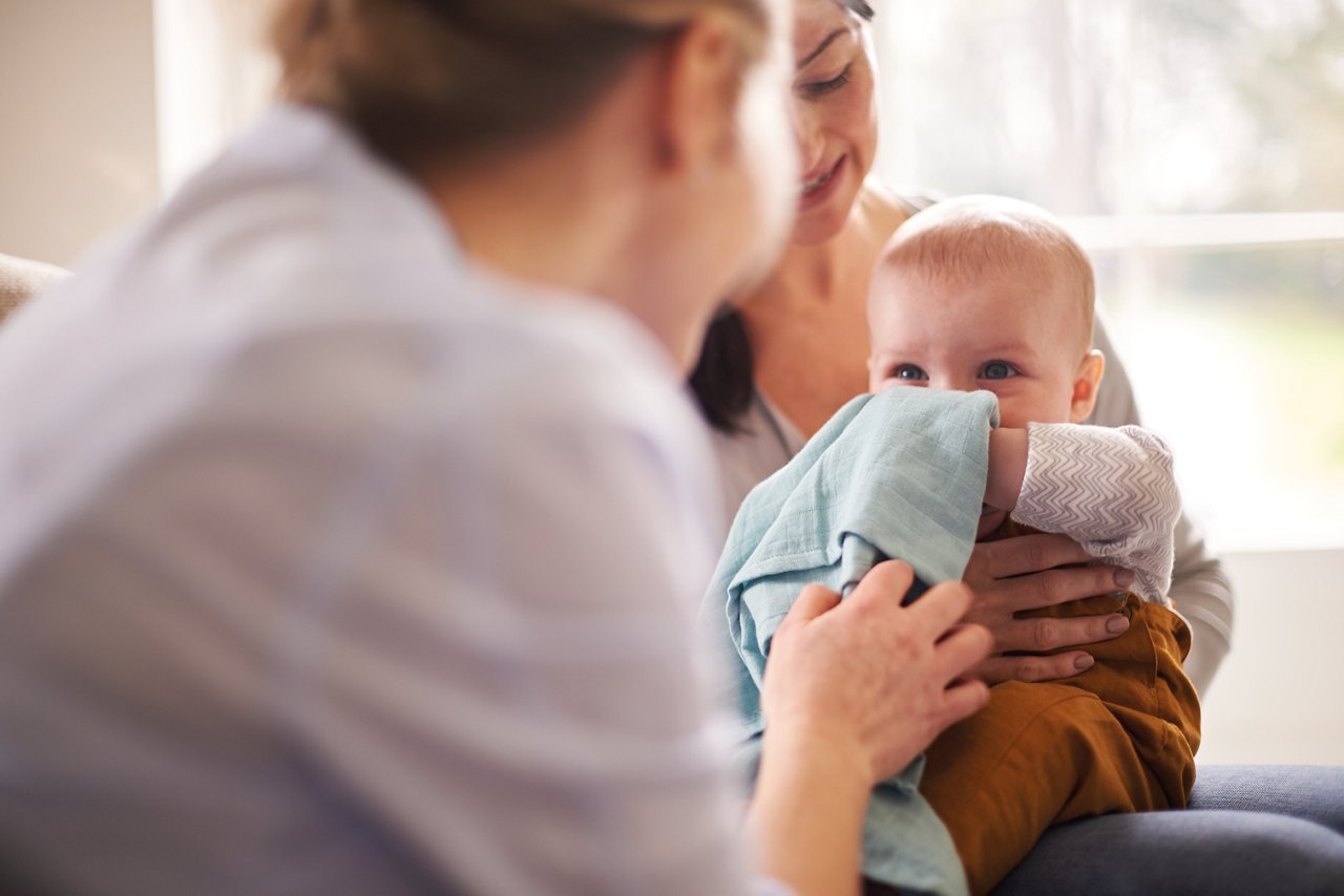 Baby die na de voeding rechtop wordt gehouden, als illustratie van reflux bij baby's en ondersteuning van het spijsverteringscomfort.