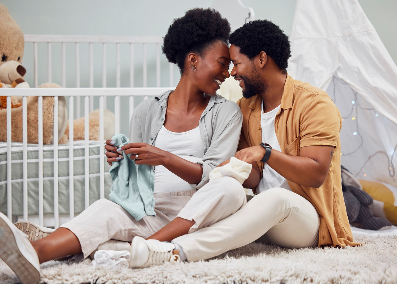 parents sitting on floor next to crib preparing nursery