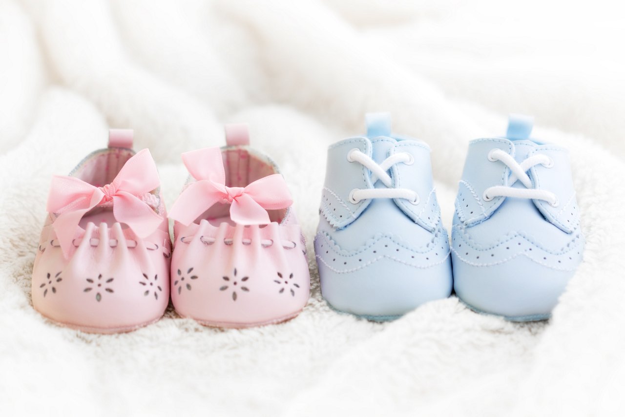 Babyschuhe in rosa und hellblau auf einer weißen Decke.