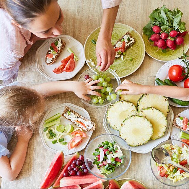 Mother having fresh fruits with son and daughter sitting at table in home