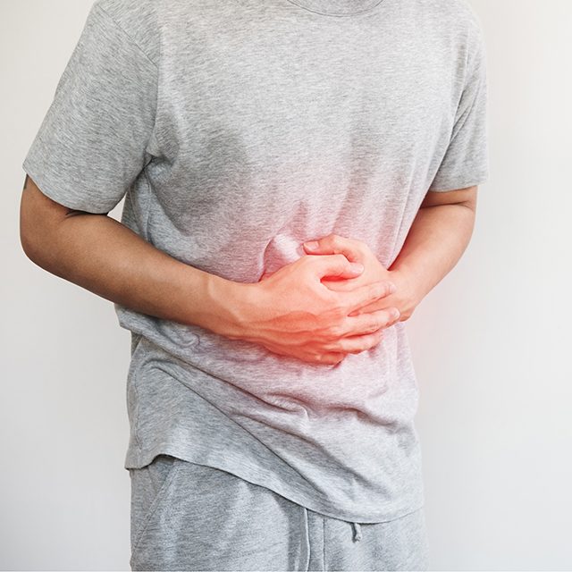 a man pressing his stomach, with red highlight of stomach pain and others stomach disease concept, on white background with copy space