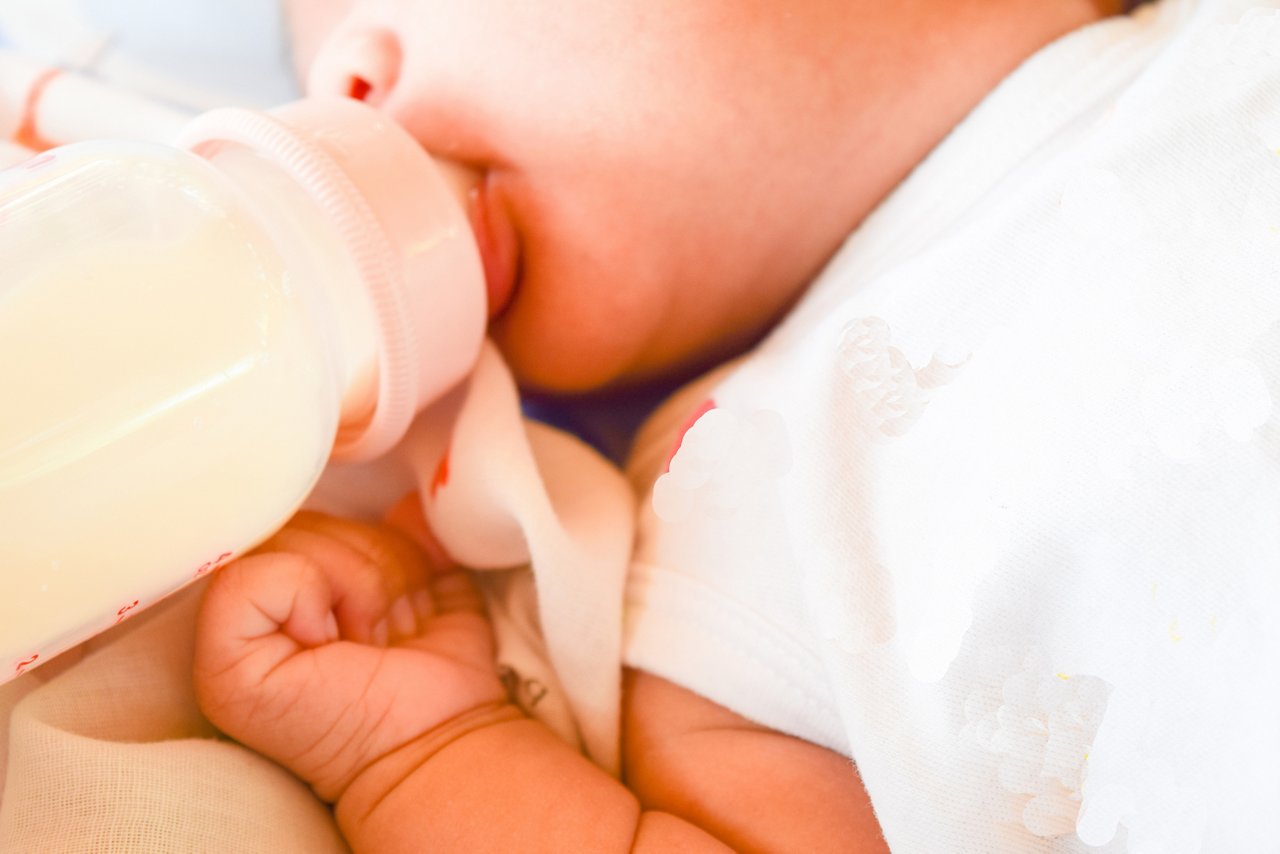 Baby mit Fläschchen auf dem Rücken liegend im Anschnitt.