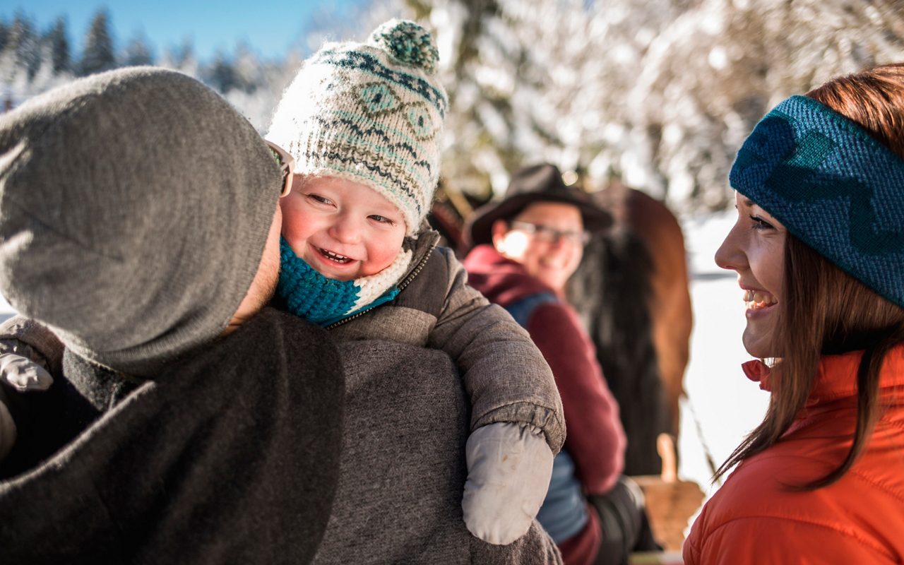 Eltern mit Baby auf dem Arm im Schnee