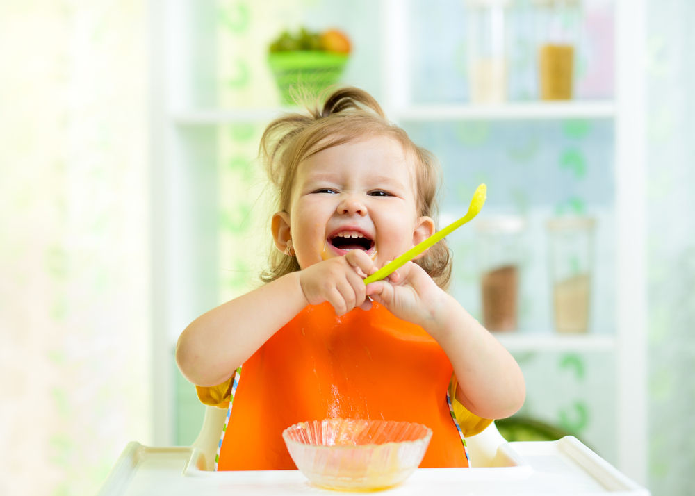 baby eating food and laughing
