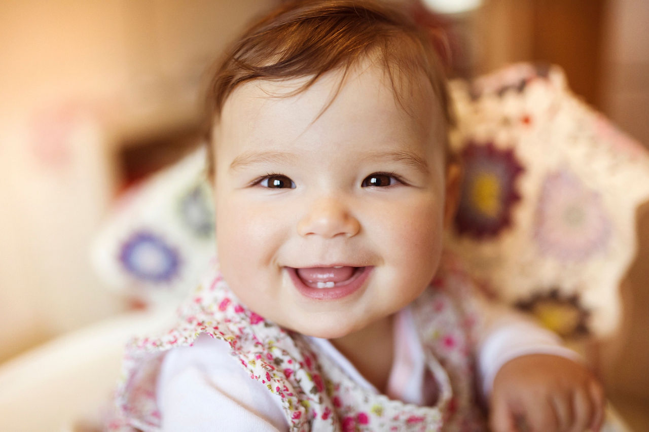 Cute little baby sitting in a high chair happy after being fed by her mother