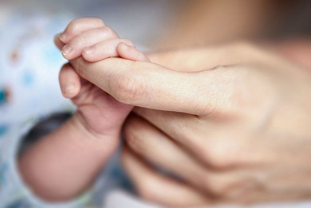 manita de bebé sosteniendo la mano de sus papás