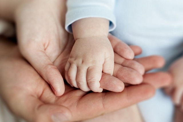 La mano del bebé sobre las palmas de los padres