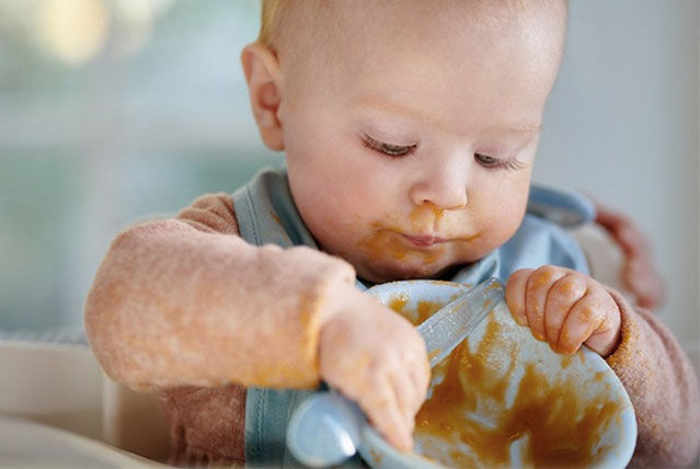 baby holding bowl of food