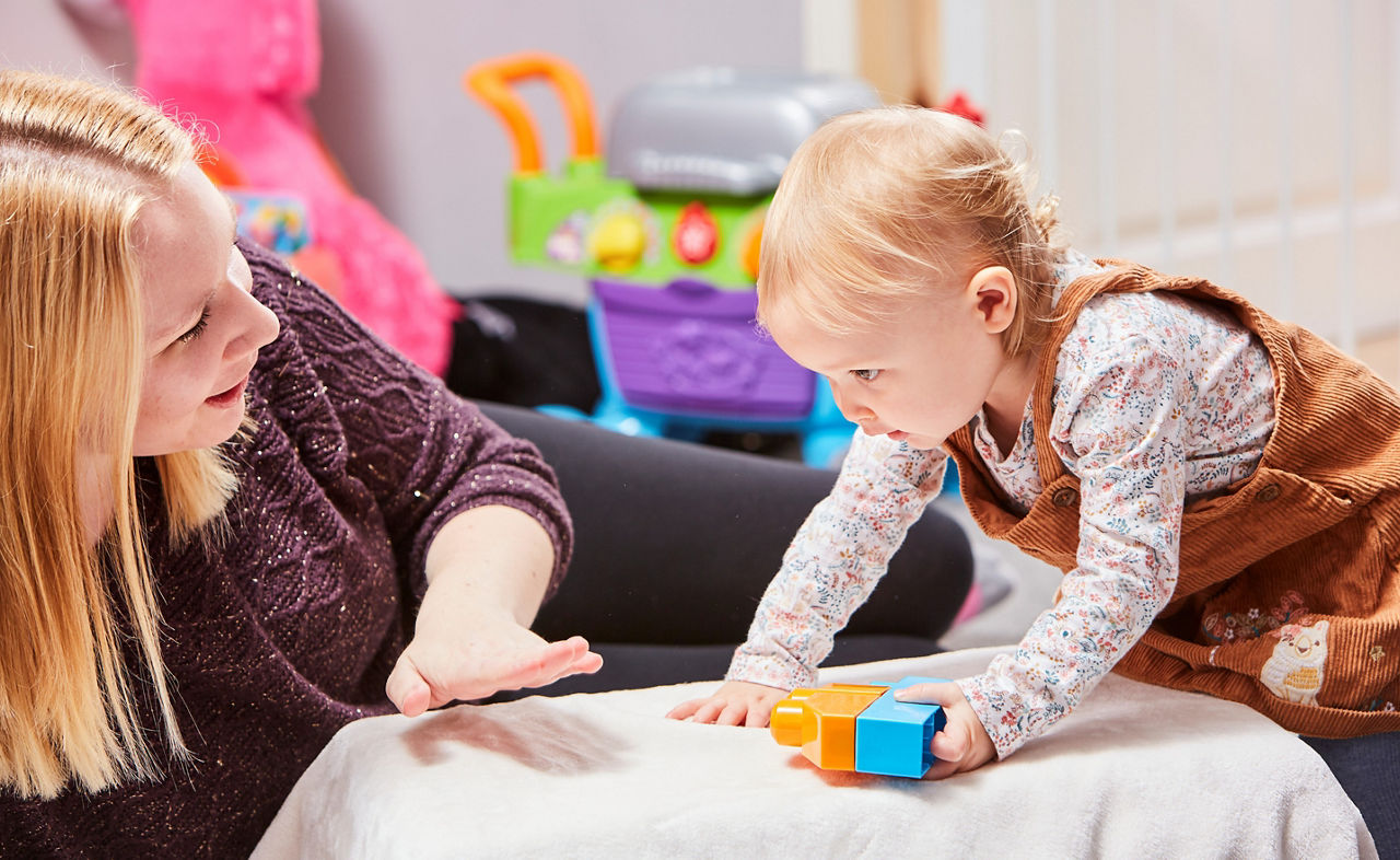 Mother playing with toddler on the bed