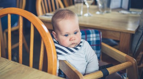 Kindje in kinderstoel in restaurant