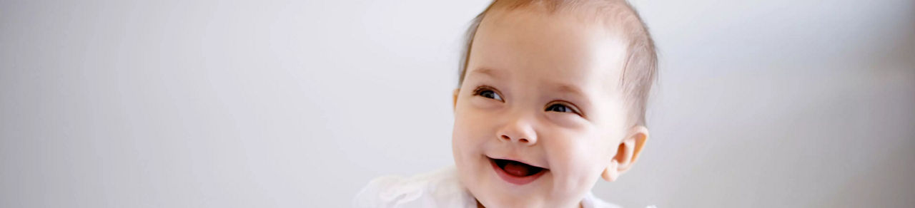 Bébé en tenue blanche sur fond neutre