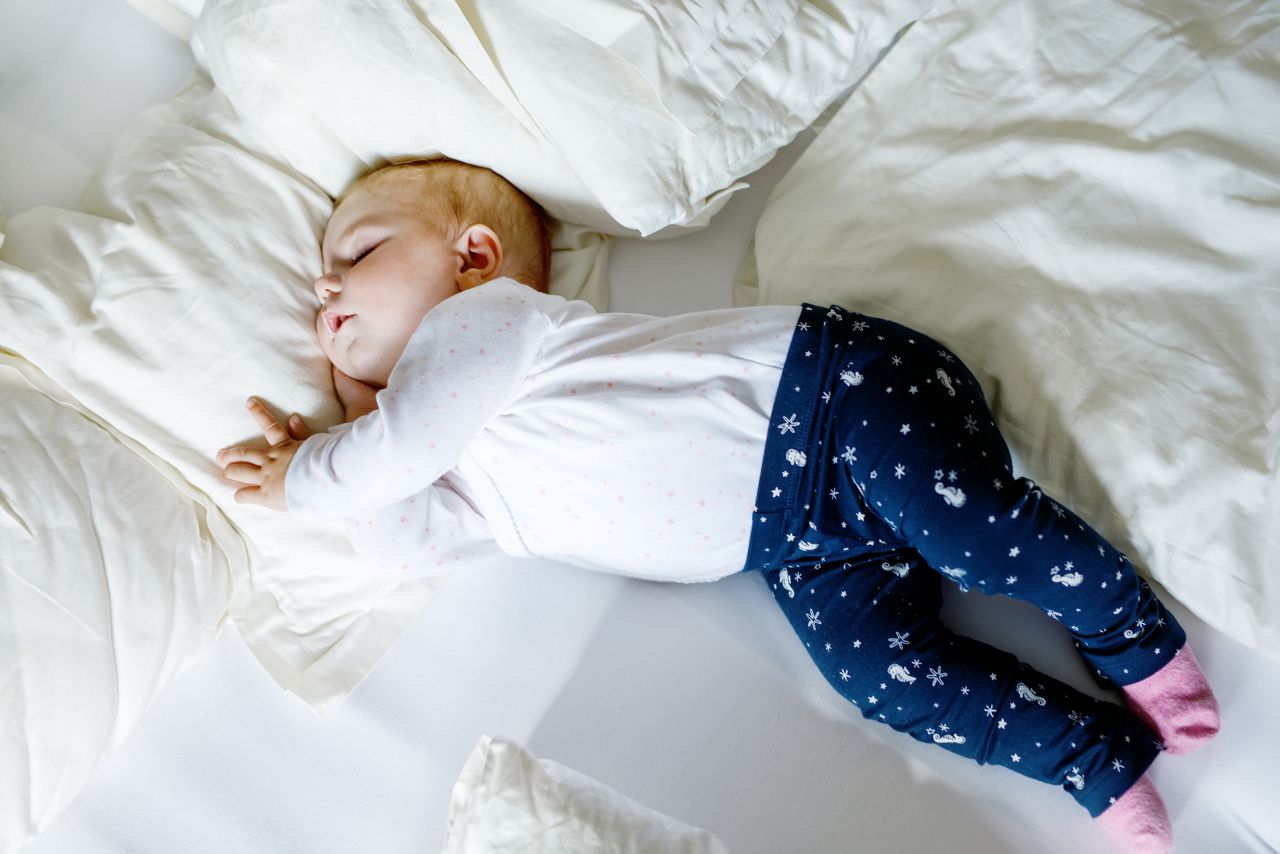 Cute adorable baby girl of 6 months sleeping peaceful in bed at home. Closeup of beautiful peaceful child, little newborn kid sleeping.