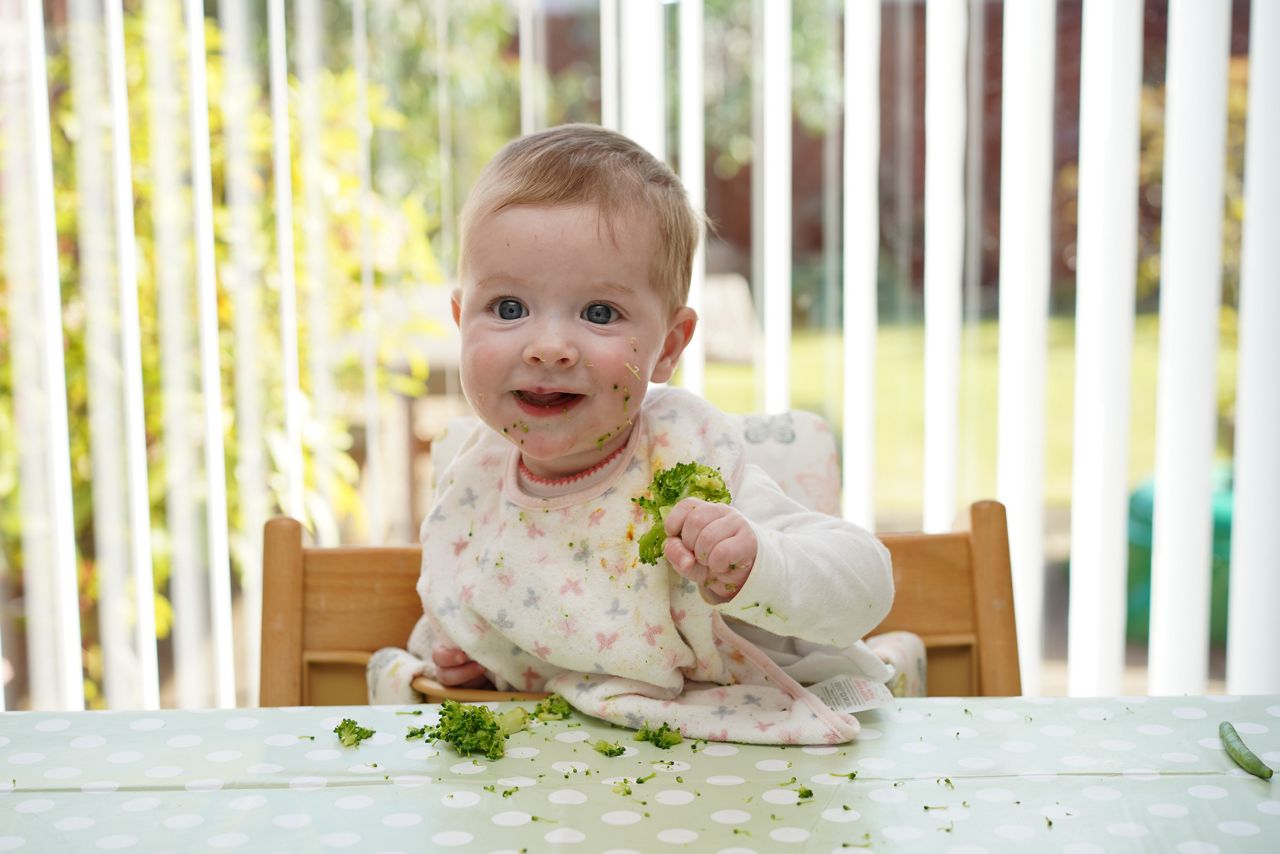 Bebe no cadeirao comendo verduras