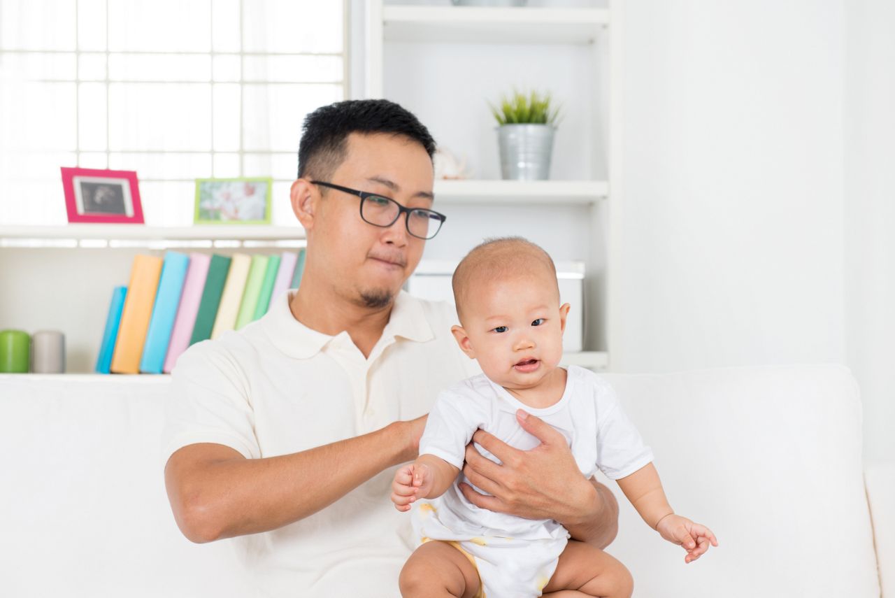 Father burping baby boy after meal, Asian family lifestyle at home.